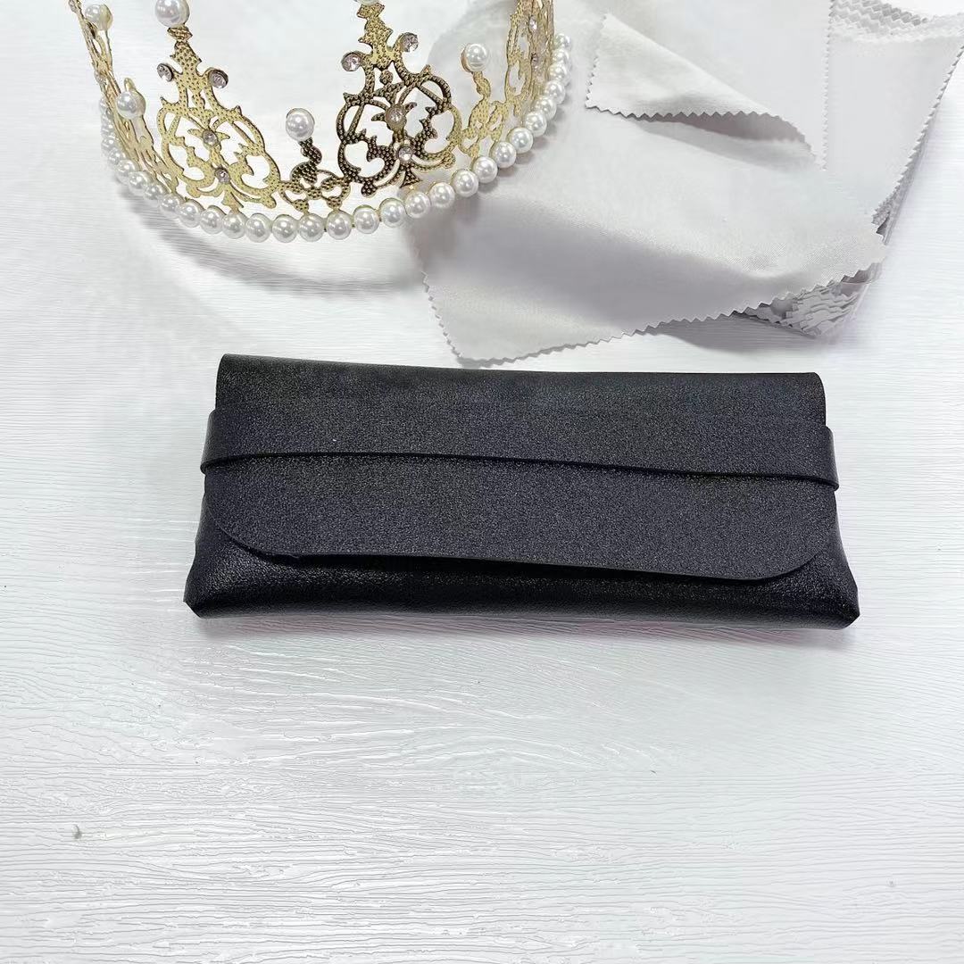 Stylish black PU sunglasses storage box on a white surface, beside a delicate crown and cloth.