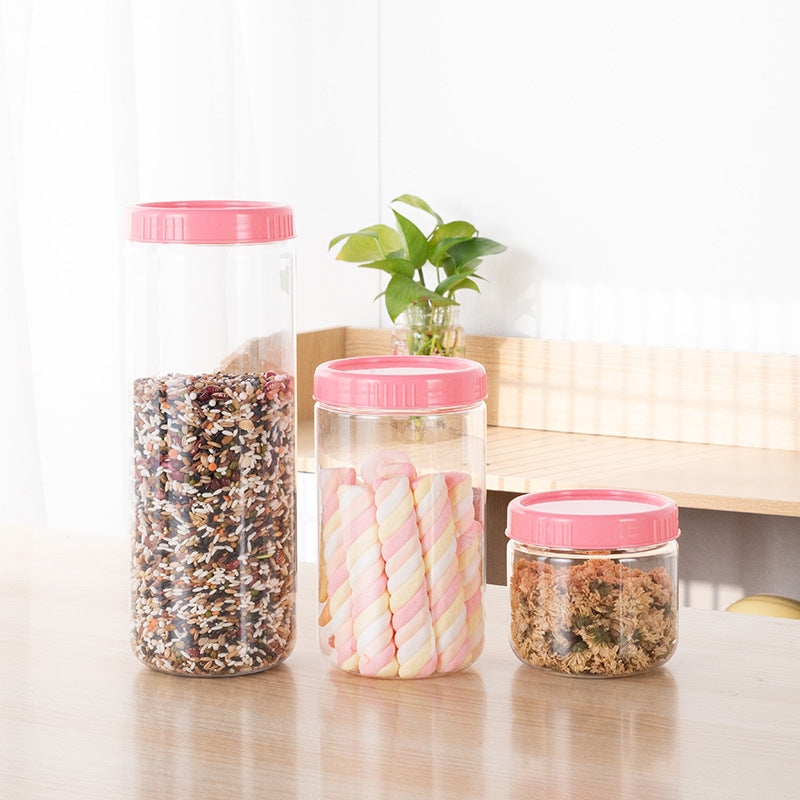 Modern minimalist grain storage boxes in pink, showcasing various shapes and sizes on a kitchen table with greenery.